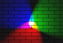 Rainbow spotlights with a white center against a brick wall.