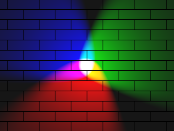 Rainbow spotlights with a white center against a brick wall.